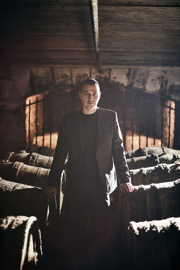 A photo of Baptiste Loiseau in a cellar, among barrels