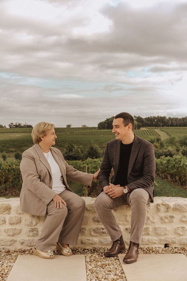 A photo of two cellar masters sitting on a low stone wall