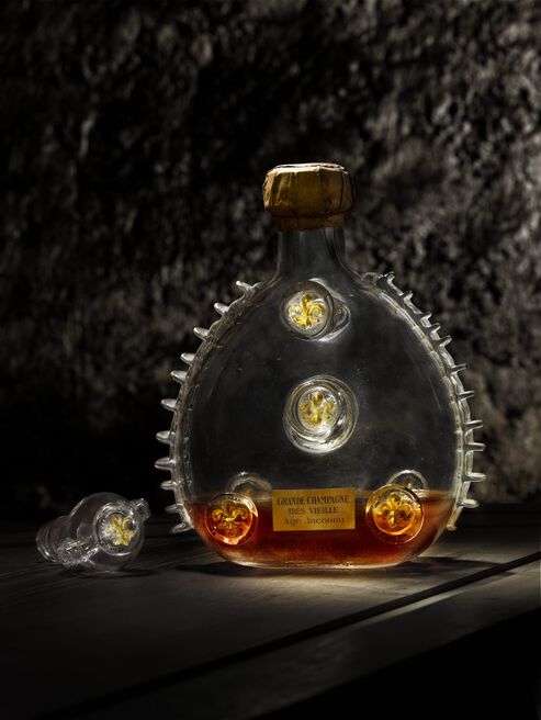 A lifestyle photo of an open decanter with 1/4 of the cognac, dark background