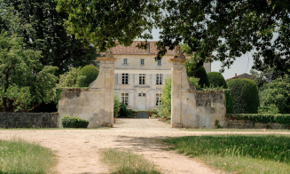 A photo of a white building seen by the entry gate