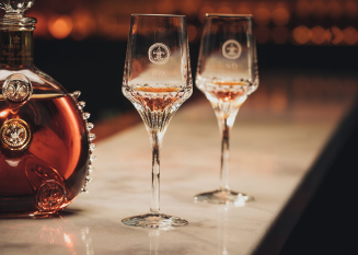 A lifestyle photo of LOUIS XIII decanter and two crystal glasses on a bar countertop