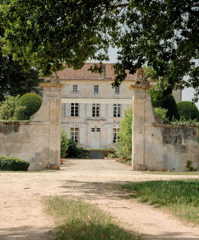 A photo of a white building seen by the entry gate