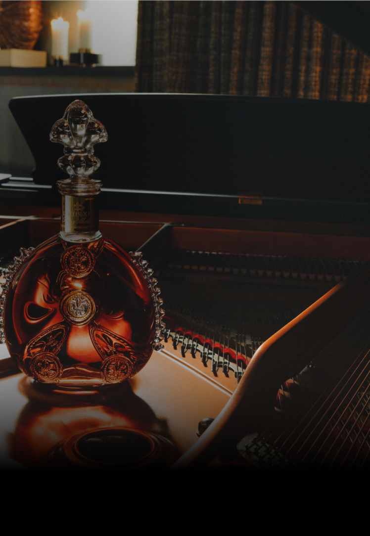 A dimmed image of a LOUIS XIII decanter on an open piano
