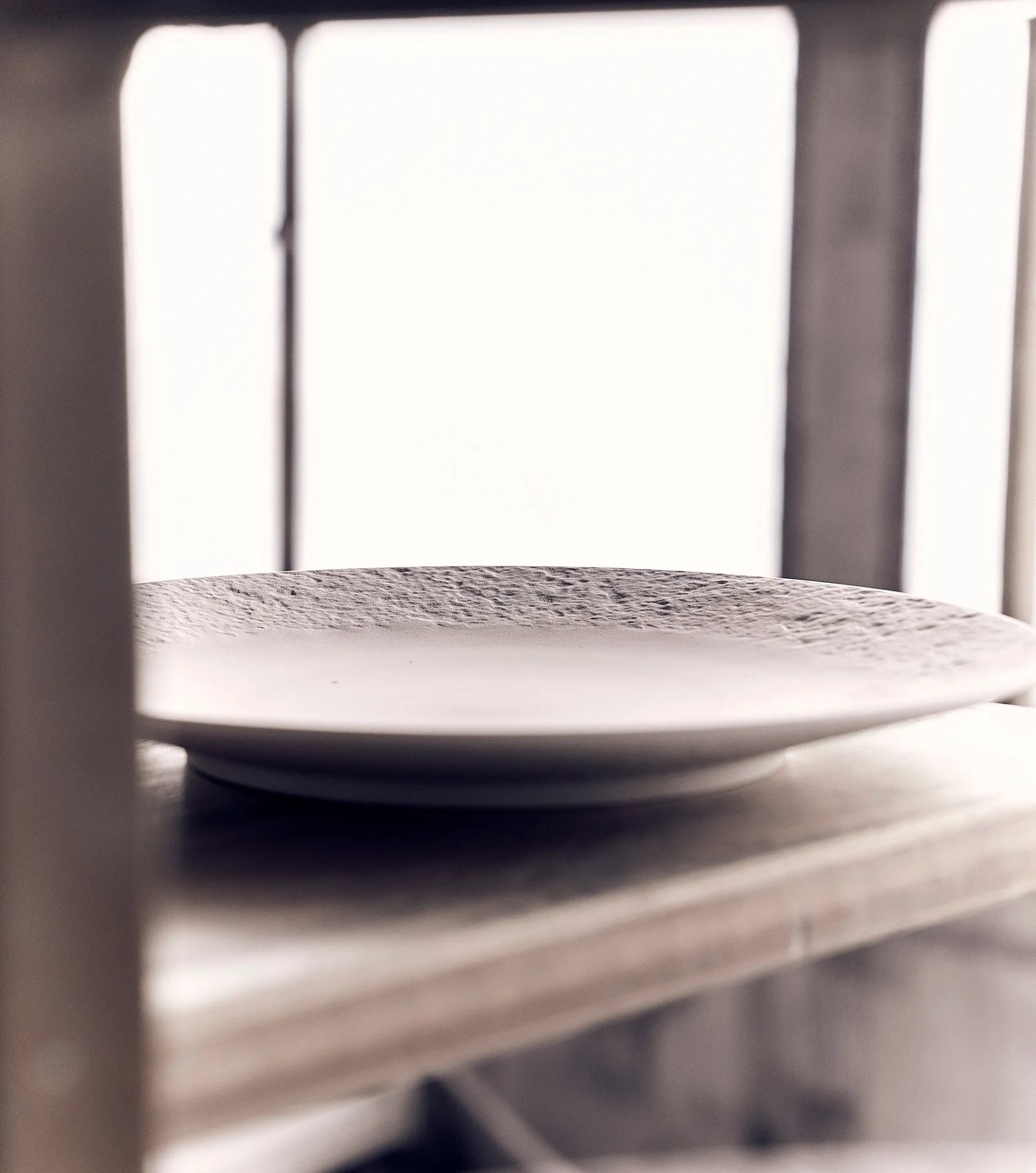 Porcelain plate from Louis XIII Soil is Our Soul collection resting on a workshop shelf, crafted by french artisans with porcelain manufacture tradition and unique decorative style.