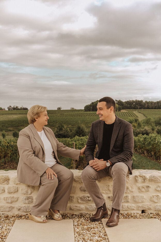 A photo of two cellar masters sitting on a low stone wall